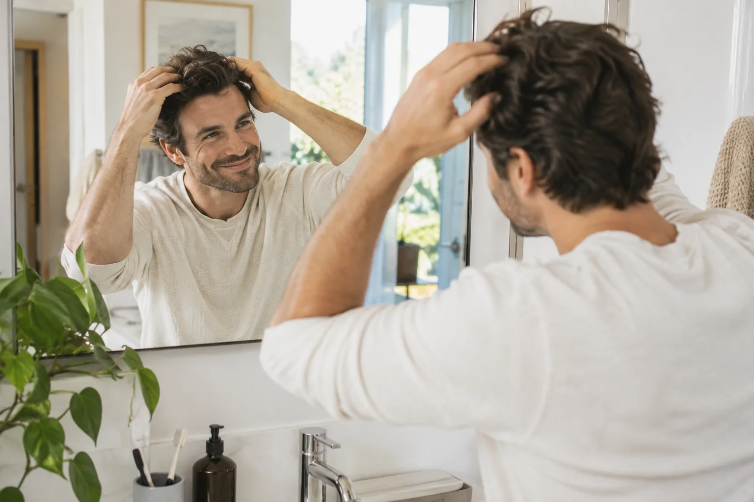 Man checking his hair in the bathroom mirror